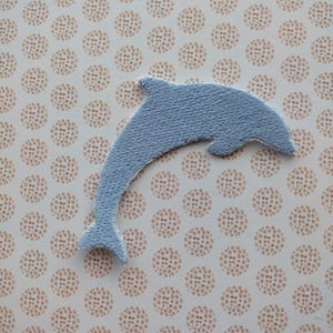 May include: A light blue felt dolphin applique, perfect for adding a nautical touch to crafts and projects.