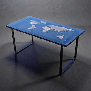 May include: A rectangular coffee table with a blue glass top featuring a world map design. The map is rendered in shades of white and gray. The table has a black metal frame.