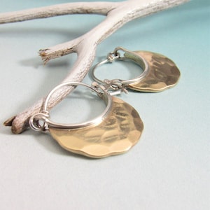May include: A pair of gold and silver hoop earrings with a hammered texture. The earrings are in the shape of a crescent moon.