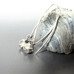 May include: A pair of silver earrings with geometric, faceted, silver beads hanging from thin silver hoops.