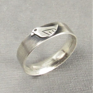 May include: A silver ring featuring a bird design. The ring has a brushed finish and a matte effect.