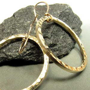 May include: A pair of gold hammered hoop earrings with a simple wire hook closure.