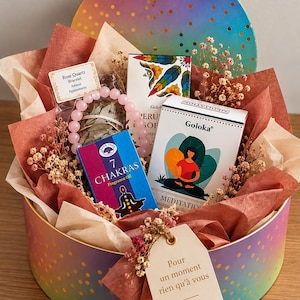 Peut inclure: Une boîte cadeau ronde à dégradé arc-en-ciel contenant du papier de soie brun, des fleurs séchées, un bracelet en perles de quartz rose, une huile parfumée 7 Chakras Green Tree et un encens Goloka Meditation avec une étiquette Pour un moment rien qu'à vous.