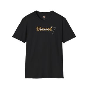 May include: A black short-sleeved t-shirt featuring the word Blessed in a gold cursive script font, with the word Momma printed in white block letters underneath, and a thin white outline of a heart shape positioned to the right of the text.