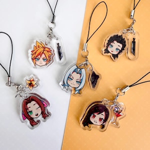 May include: Clear acrylic charms featuring anime-style character portraits with black lanyards. The charms depict characters with various hair colours and expressions, along with accompanying charms like a sword, flower, and wings. The background is white and orange.