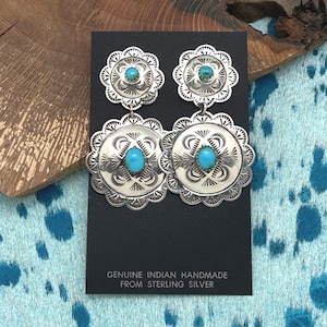 Könnte beinhalten: Ohrringe aus Sterlingsilber mit Türkissteinen. Die Ohrringe haben ein florales Design mit einem zentralen Türkisstein in jedem der kreisförmigen Elemente. Der Text unten lautet "GENUINE INDIAN HANDMADE FROM STERLING SILVER."