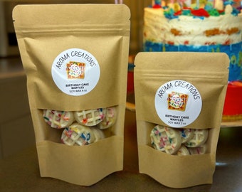 May include: Two bags of soy wax melts shaped like birthday cake waffles. The larger bag is labeled "Aroma Creations Birthday Cake Waffles Soy Wax 4 oz" and the smaller bag is labeled "Aroma Creations Birthday Cake Waffles Soy Wax 2 oz".