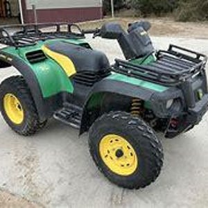 Może przedstawiać: Zielono-czarny ATV z żółtym paskiem i czarnym i srebrnym bagażnikiem dachowym.