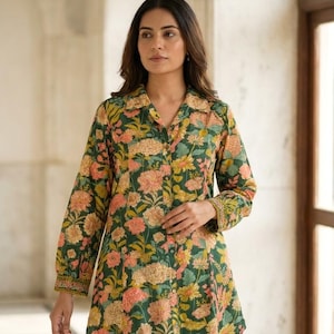 Könnte beinhalten: Eine langärmelige, durchgeknöpfte Tunika mit dunkelgrünem Grund und einem mehrfarbigen Blumenmuster in Rosa-, Gelb- und Orangetönen. Die Tunika hat einen klassischen Kragen und wird mit einer grünen Hose kombiniert, die ein vertikales weißes Streifenmuster aufweist.