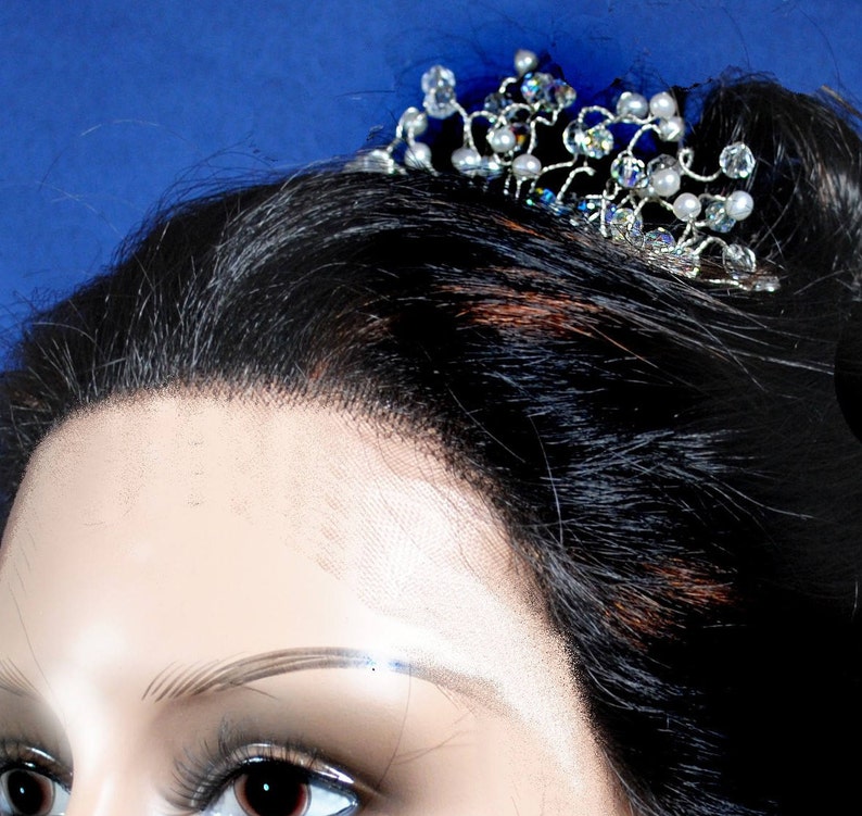 Puede incluir: Un peine de pelo plateado con cristales y perlas transparentes y blancas. El peine est&aacute; dise&ntilde;ado con un delicado patr&oacute;n de vid.