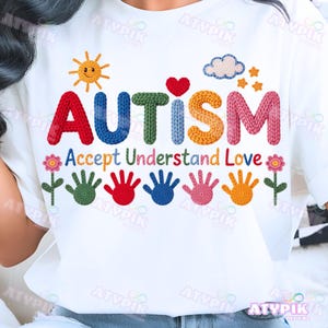 Puede incluir: Camiseta blanca con la palabra "AUTISMO" en letras coloridas y texturizadas. Debajo, las palabras "Accept Understand Love" están escritas. El diseño incluye un sol, un corazón, una nube, estrellas, flores y huellas de manos.