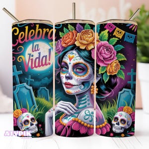 May include: A Day of the Dead themed tumbler featuring a vibrant illustration of a woman with sugar skull makeup, adorned with flowers. The tumbler has the text "Celebra la Vida!" and includes a straw.