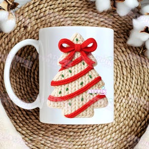 May include: White ceramic mug featuring a Christmas tree design. The tree is cream-colored with red ribbon accents and a red bow at the top. Green dots are scattered throughout the tree. The mug has a white handle.