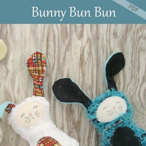 May include: Two handmade bunny plushies. One is white with a patterned ear and belly, the other is blue with black accents. The text "Bunny Bun Bun" is at the top, and "Patchwork Posse" is at the bottom.
