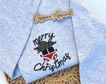 Puede incluir: Una sudadera gris jaspeado claro con un diseño bordado de una furgoneta roja y blanca que lleva un árbol de Navidad verde en el techo. El texto "merry Christmas" está bordado en letra cursiva negra. Una etiqueta de madera dice "Cappora Apparel".