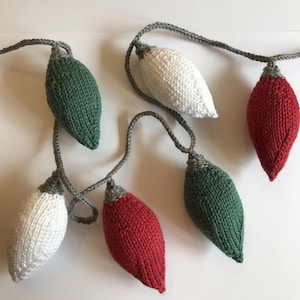 Puede incluir: Una guirnalda de bombillas de luz de punto en rojo, verde y blanco. Las bombillas están enhebradas con hilo gris.