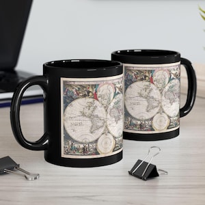May include: Two black ceramic mugs with a vintage world map design. The map is in shades of brown, blue, and red with a white background. The mugs are 11 ounces each.