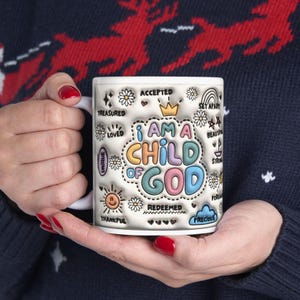 May include: White ceramic mug with a colorful design that says "I am a child of God" surrounded by words like "treasured", "loved", "accepted", "unique", "strong", "beautiful", "forgiven", "redeemed", "precious", and "thankful".