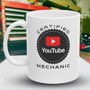May include: White ceramic coffee mug with a black and white graphic of a YouTube logo inside a carbon fiber pattern. The text "CERTIFIED YOUTUBE MECHANIC" is printed on the mug.
