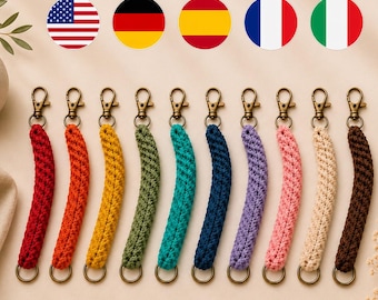 Puede incluir: Diez llaveros de macramé en fila, cada uno en un color sólido diferente: rojo, naranja, amarillo, verde oliva, verde azulado, azul marino, morado, rosa, crema y marrón. Cada llavero tiene un mosquetón de tono bronce y una anilla metálica.