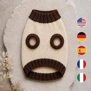 May include: A cream-colored knit sweater for a pet featuring a dark brown ribbed collar, dark brown ribbed sleeve openings, and a dark brown ribbed hem. The garment is constructed with a thick, textured knit pattern and a rounded neckline.