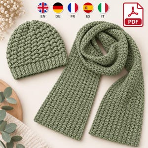 Puede incluir: Un gorro de ganchillo color verde salvia y una bufanda larga a juego. Ambos artículos presentan un patrón de puntos texturizados consistente. El gorro tiene un borde acanalado, mientras que la bufanda es rectangular y uniforme.