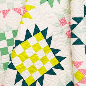May include: A quilt with a patchwork design featuring a variety of colours and patterns, including green, yellow, white, and pink. The quilt is made up of squares and triangles, and the fabric is quilted with a wavy pattern.
