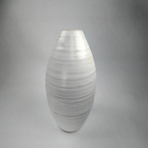 May include: White ceramic vase with a striped design. The vase is oval shaped and has a smooth, glossy finish.