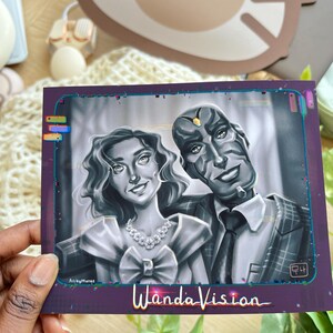 May include: A grayscale illustration of two characters from WandaVision. The woman wears a dress and necklace, while the man is in a suit. The artwork is framed in a purple border with the show's title at the bottom.