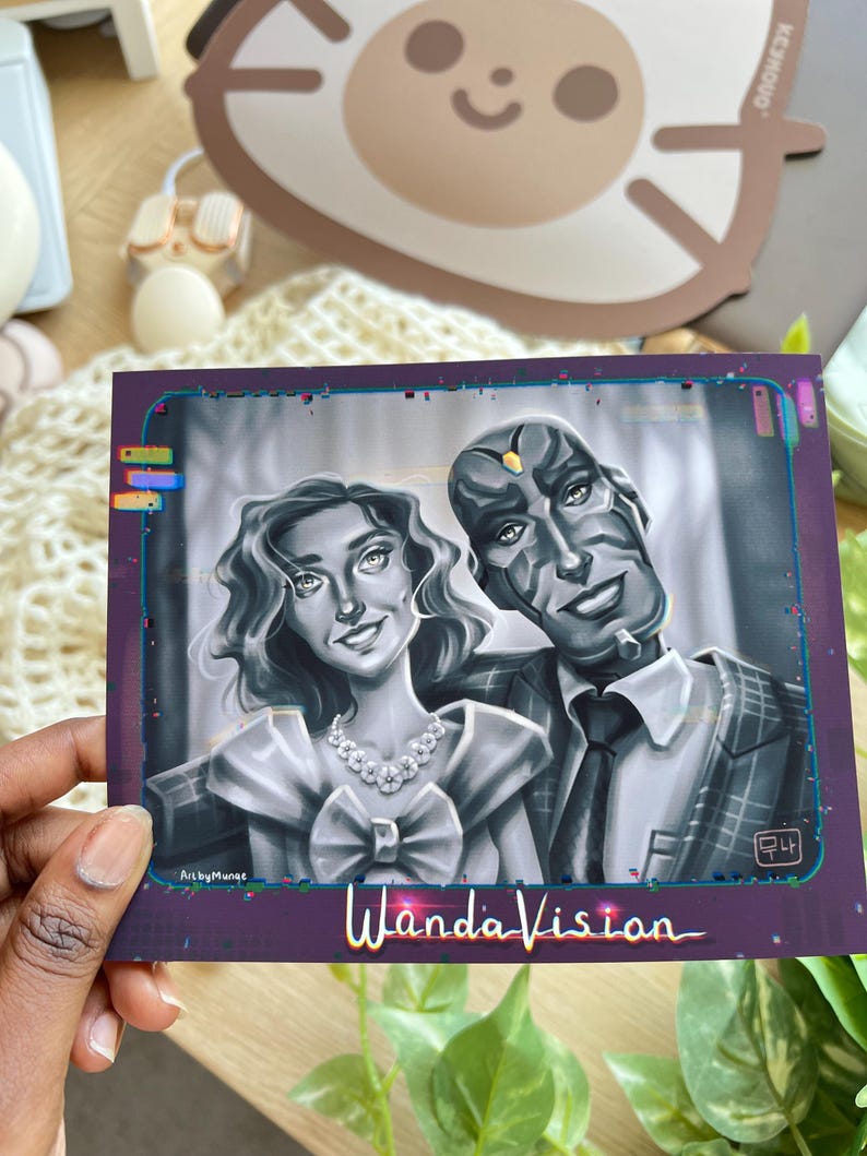 May include: A grayscale illustration of two characters from WandaVision. The woman wears a dress and necklace, while the man is in a suit. The artwork is framed in a purple border with the show's title at the bottom.