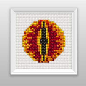 Puede incluir: Primer plano de un ojo rojo, naranja y amarillo con una pupila negra, representado en un estilo pixelado. El ojo está enmarcado por un borde blanco.