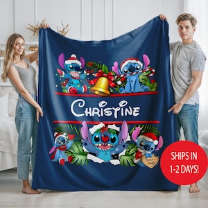 May include: A navy blue blanket with Stitch characters in Santa hats and festive decorations. The blanket displays the name "Christine" in white script. A red circle with white text reads "SHIPS IN 1-2 DAYS!"