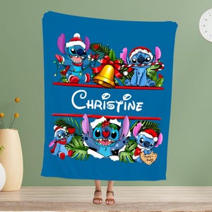 May include: A blue blanket with a Christmas-themed design featuring Stitch from Lilo & Stitch. The blanket has the name "Christine" and Stitch is wearing a Santa hat and holding festive decorations. A seasonal, festive blanket.