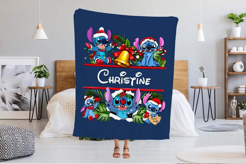 May include: A navy blue blanket featuring the character Stitch in a Christmas theme. The blanket has the name "Christine" in white script. Stitch is depicted wearing a Santa hat and surrounded by festive decorations.