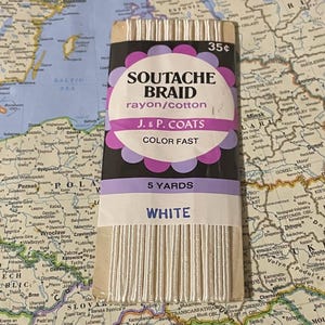 May include: A package of white soutache braid, a rayon and cotton trim, with the text "SOUTACHE BRAID" and "WHITE". The package is 5 yards long and has a price tag of 35¢.