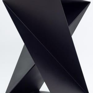 May include: A black, geometric, metal side table with a unique, folded design. The table has a square base and a triangular top.