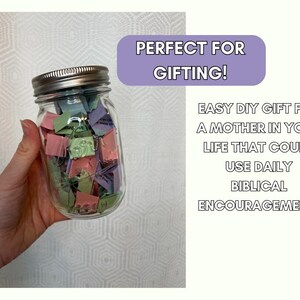Op de afbeelding: Een glazen pot gevuld met kleurrijke papiertjes, elk met een bijbelvers erop. De pot is gelabeld met "Perfect om cadeau te geven!" en de tekst eronder luidt "Makkelijk DIY-cadeau voor een moeder in je leven die dagelijks bijbelse aanmoediging kan gebruiken!"