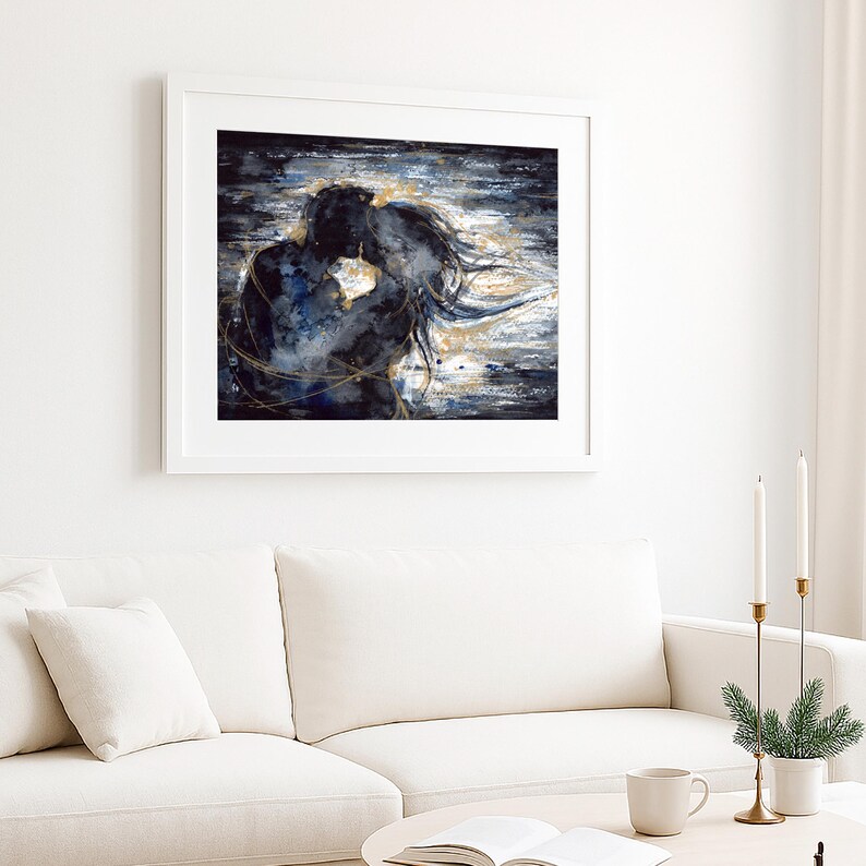 Op de afbeelding: Een ingelijste kunstdruk met een abstract schilderij van twee figuren in een nauwe omhelzing. Het kunstwerk gebruikt een kleurenpalet van donker marineblauw en zwart met wervelende gouden metallic accenten die de silhouetten benadrukken.