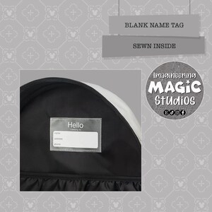 Puede incluir: Mochila negra con una etiqueta de nombre blanca cosida en el interior. La etiqueta de nombre tiene las palabras "Hello I belong to" y espacios para el nombre, la direcci&oacute;n y el n&uacute;mero de tel&eacute;fono. La mochila tiene un parche blanco con las palabras "Imagineering Magic Studios" y iconos de redes sociales.