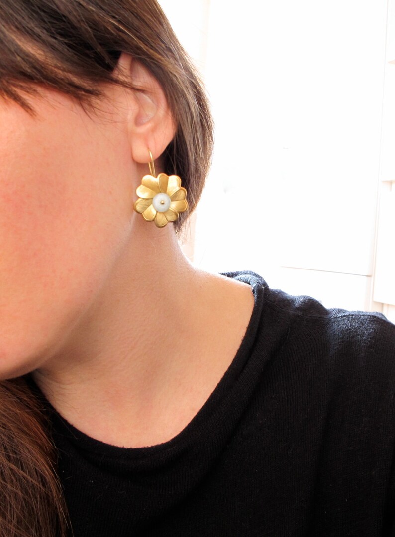 May include: Gold flower-shaped earrings with a white pearl center.