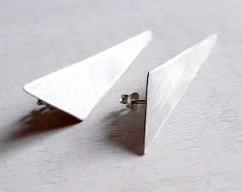 May include: A pair of silver triangle shaped earrings with a brushed finish.