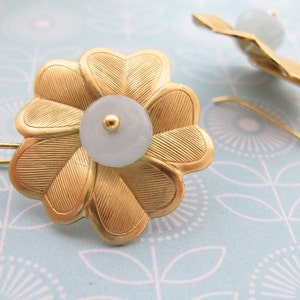 May include: A pair of gold flower-shaped earrings with a light blue stone in the center of each flower.