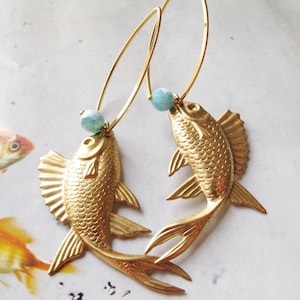 May include: Gold fish earrings with turquoise beads. The fish are detailed with scales and fins.
