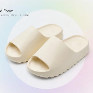 May include: A pair of cream-coloured slide sandals. The sandals feature a chunky sole and a single strap. The image includes the text "Cloud Foam" and "All over printing. We edit & design."