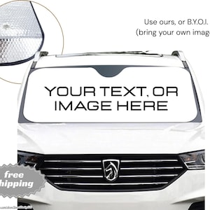 Op de afbeelding: Witte auto voorruit zonnescherm met de tekst "YOUR TEXT, OR IMAGE HERE" in vette zwarte letters. Het zonnescherm heeft een zilveren reflecterende oppervlakte en een zwarte rand. Een kleine afbeelding leest "free shipping".