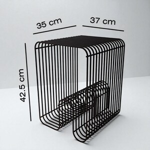 May include: Black metal stool with a rectangular seat and a unique, curved base. The stool measures 35 cm x 37 cm (13.8 x 14.6 inches) at the top and is 42.5 cm (16.7 inches) tall. The design features vertical bars for the sides and seat.