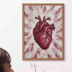 Könnte beinhalten: Ein gerahmtes Kunstwerk mit einer detaillierten, realistischen Darstellung eines menschlichen Herzens in Rottönen. Das Herz ist vor einem Hintergrund aus strukturierten Pinselstrichen in Rosa und Weiß zentriert, in einem Holzrahmen.