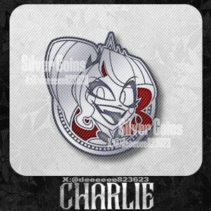 May include: A silver-colored pin featuring a cartoon character with white hair, red accents, and a smiling expression. The pin has a circular border with text that reads "Silver Coins" and "CHARLIE".