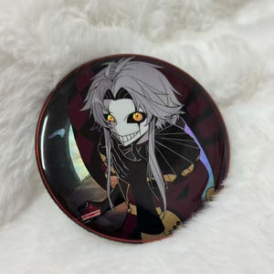 Könnte beinhalten: Ein runder Button mit dunklem Hintergrund und einer Charakterillustration. Die Figur hat weiße Haare, ein schwarzes Outfit und leuchtend orangefarbene Augen. Der Button hat einen roten Rand und ein glänzendes Finish.