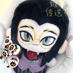 May include: Plush doll featuring a character with black hair, gold-rimmed glasses, and a purple suit. The doll has embroidered facial features and a red tie. The text "糖分 传送带" is visible on the doll. A cluster of cartoonish egg-shaped figures is also present.